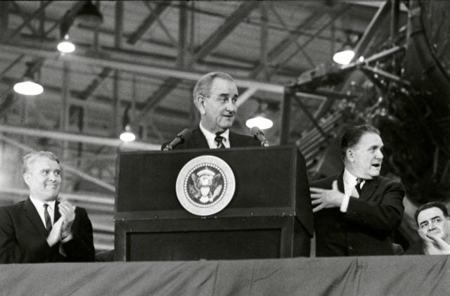 Marshall Space Flight Center (MSFC) Director Dr. Wernher von Braun (left) applauds President Lyndon Johnson's remarks during an address to 26,000 workers at the MSFC Michoud Assembly Facility on December 13, 1967. At right is NASA Administrator James Webb.
